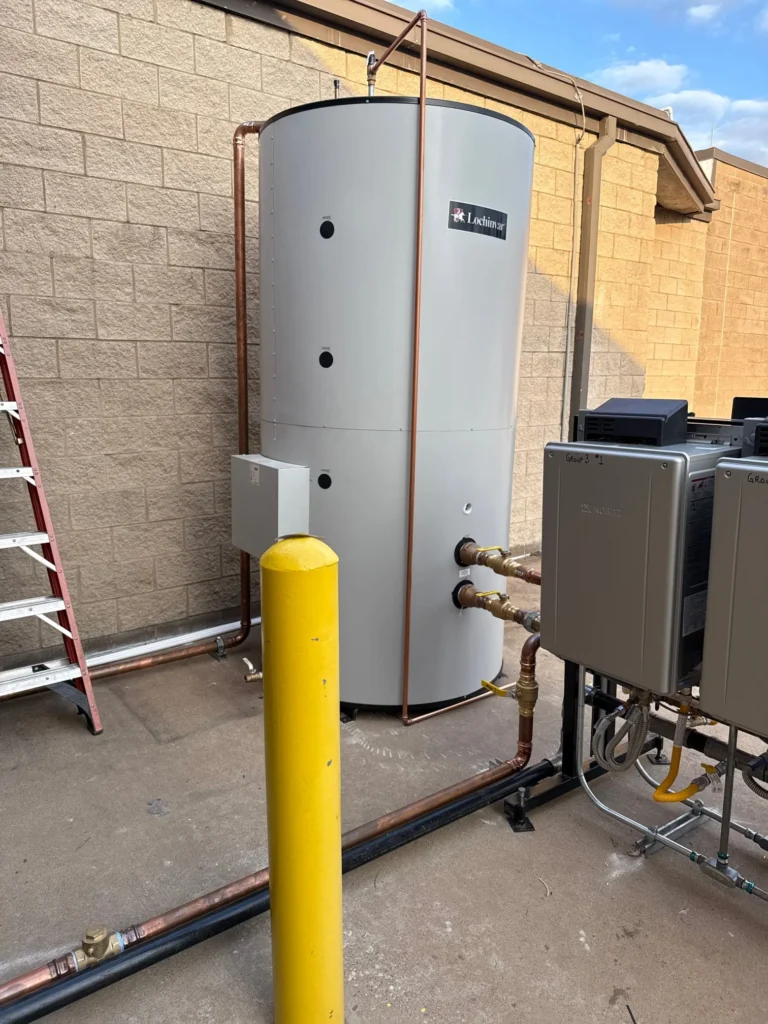 A commercial plumbing installation featuring a Lochinvar water storage tank connected to multiple tankless water heaters.