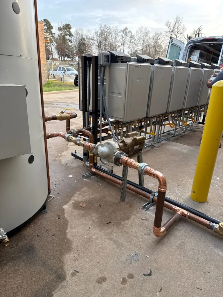 Commercial plumbing installation with a Lochinvar water storage tank, multiple tankless water heaters, and copper piping connected to a pump.