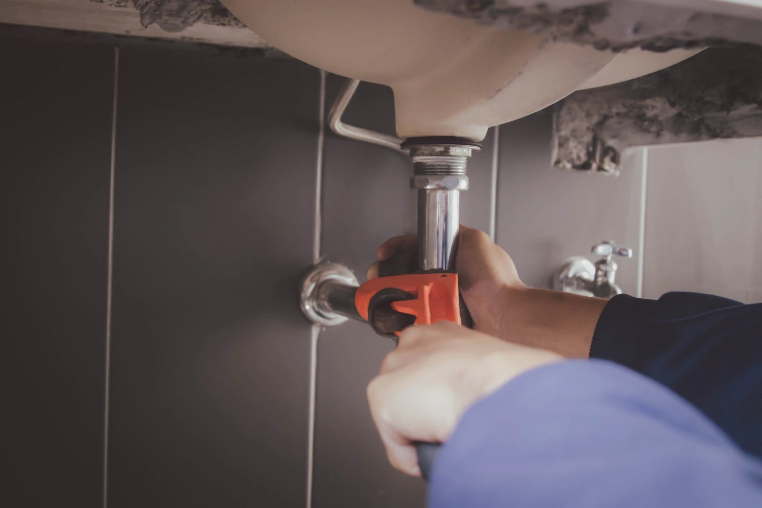 A bathroom sink faucet with a wrench attached suggesting a repair or replacement process is underway