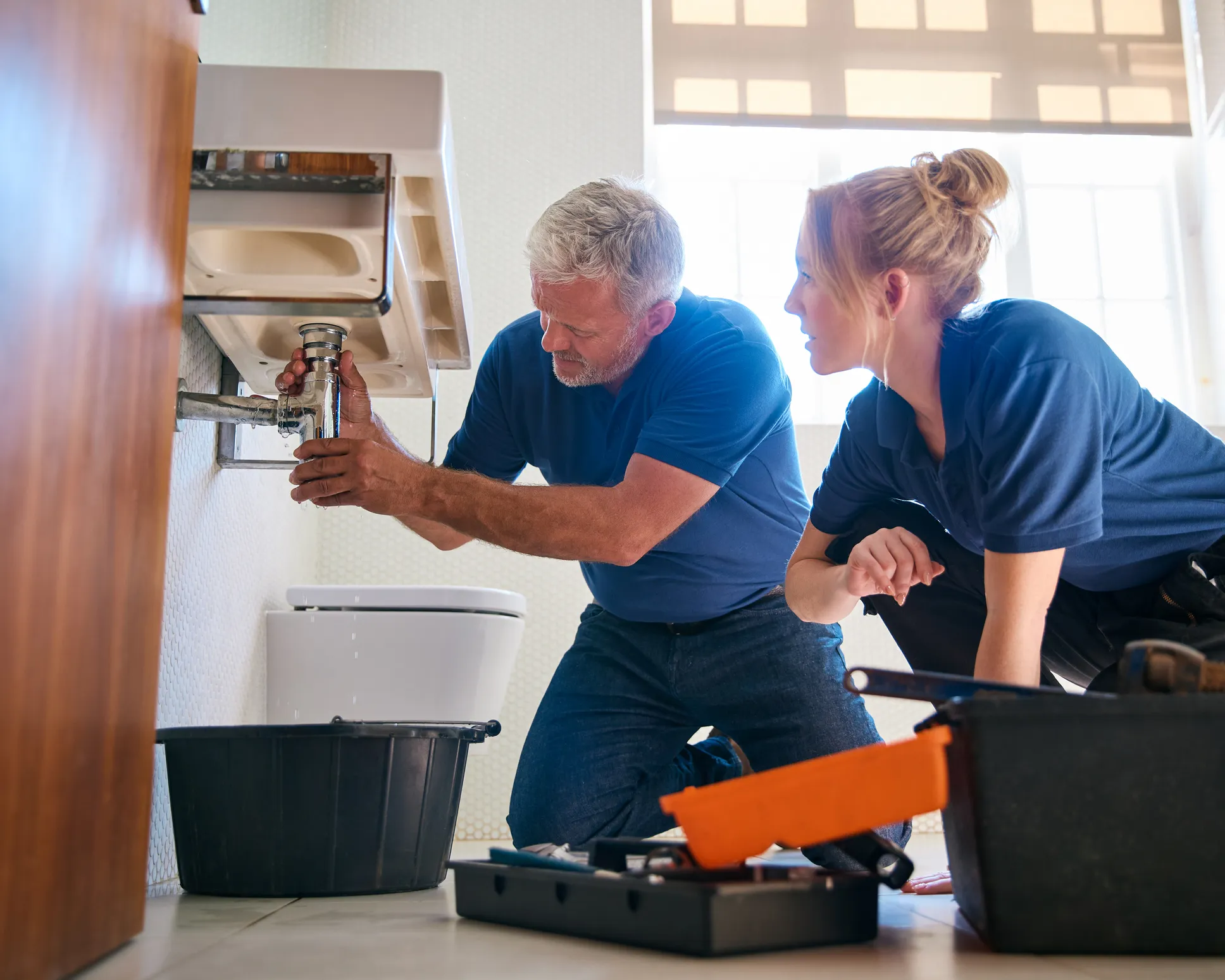 Two plumber repairing a faucet and sink in a corporate office