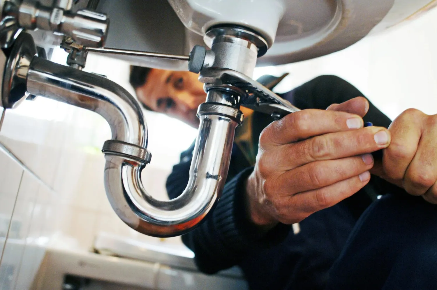 A plumber fixing a sink inside a washroom