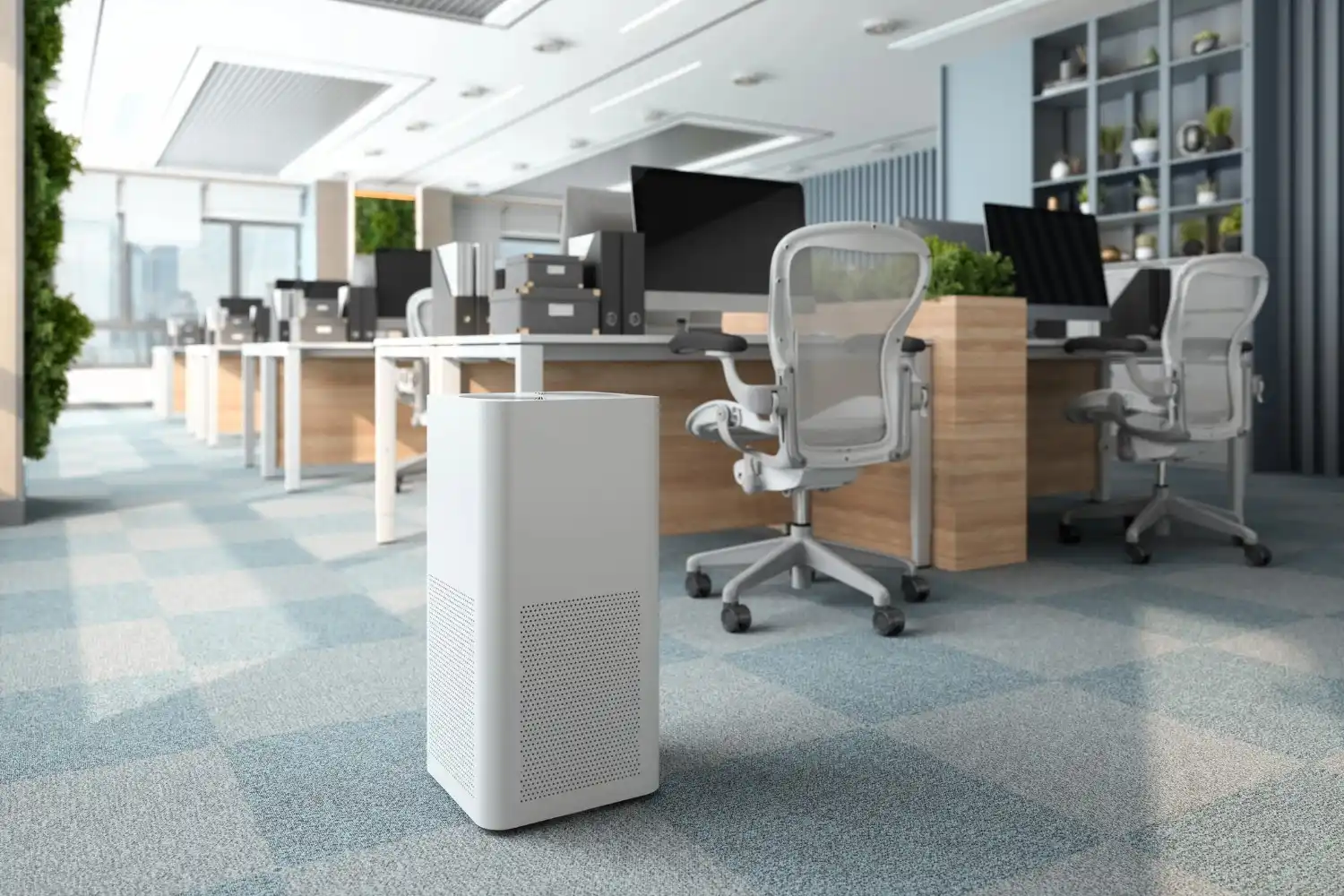 A white rectangular whole house humidifier with a perforated lower section stands on a blue and white checkered carpet in a modern office space with multiple desks and chairs