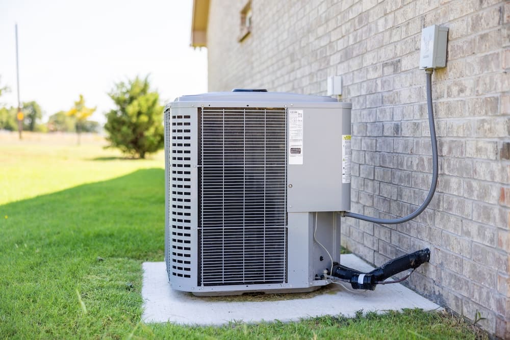 air conditioning unit on side of a brick home in green grass